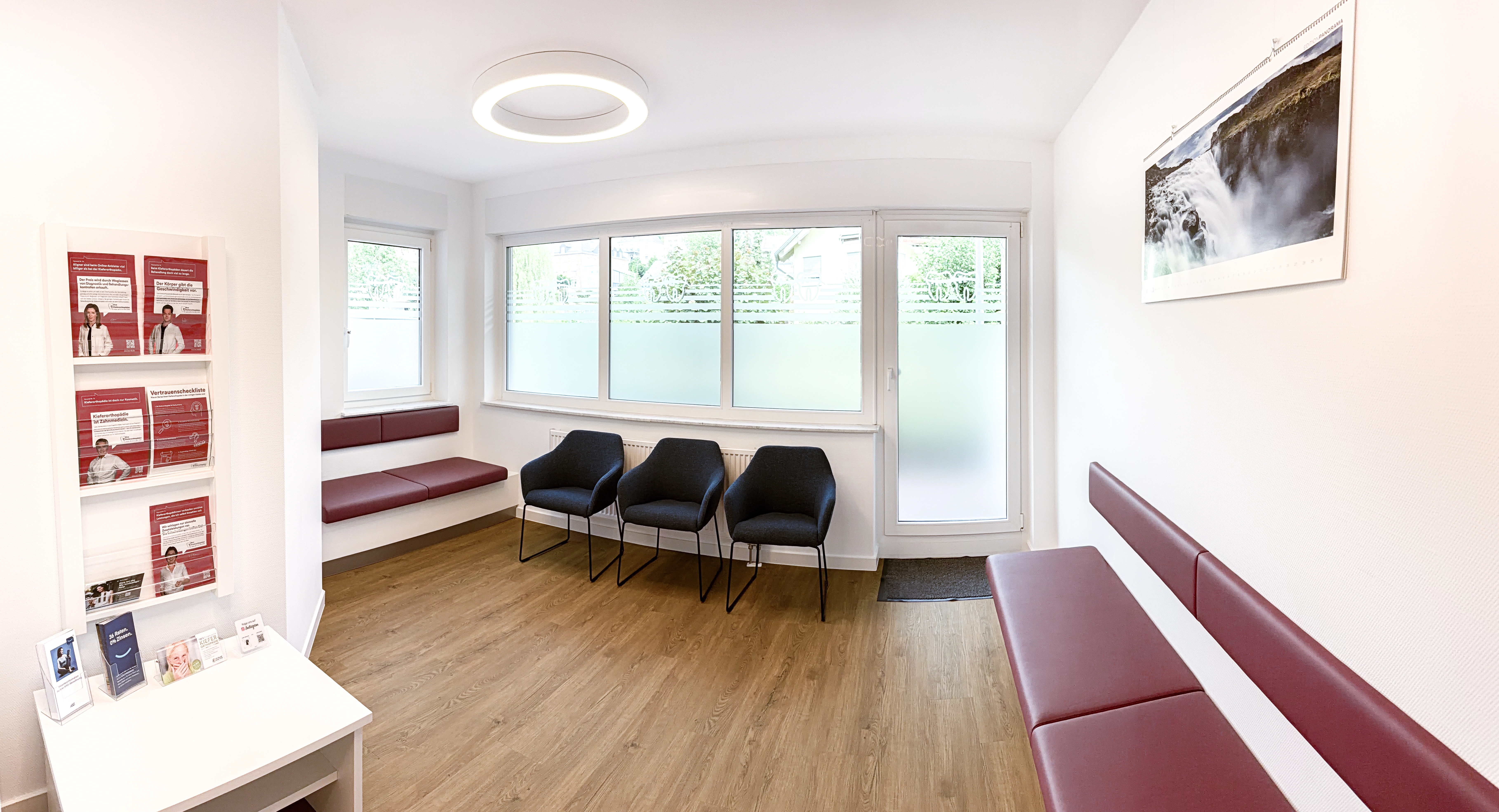 Heller Wartebereich der kieferorthopädischen Praxis KFO Saarburg mit Sitzplätzen und Informationsmaterialien.