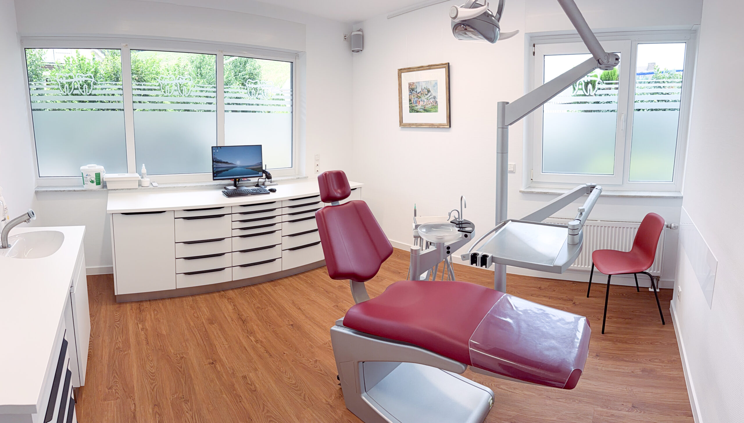 Helles und modern ausgestattetes Behandlungszimmer einer kieferorthopädischen Praxis mit Behandlungsstuhl und Behandlungsleuchte.