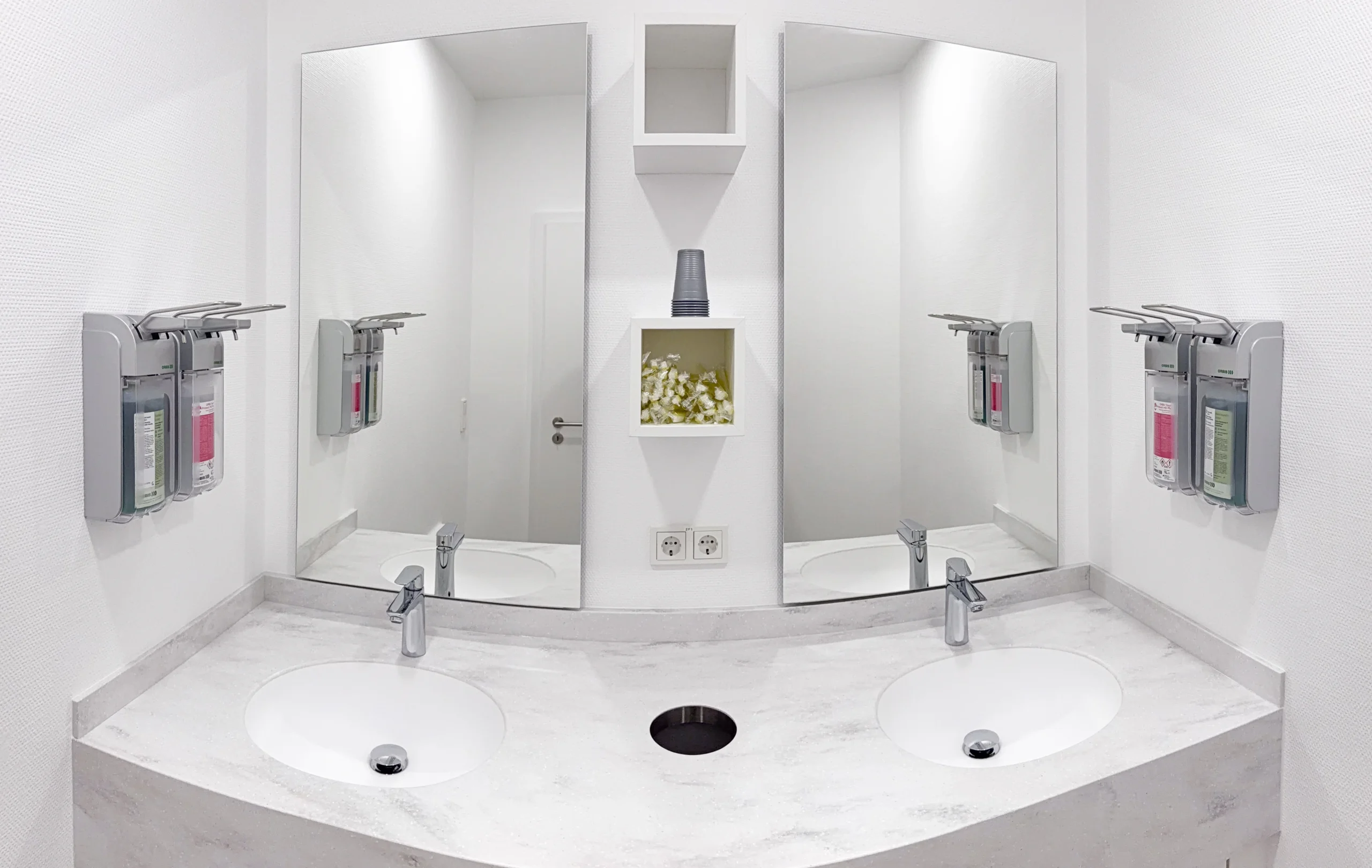 Moderne Zahnputzstation mit zwei Waschbecken und Spiegeln in der kieferorthopädischen Praxis.