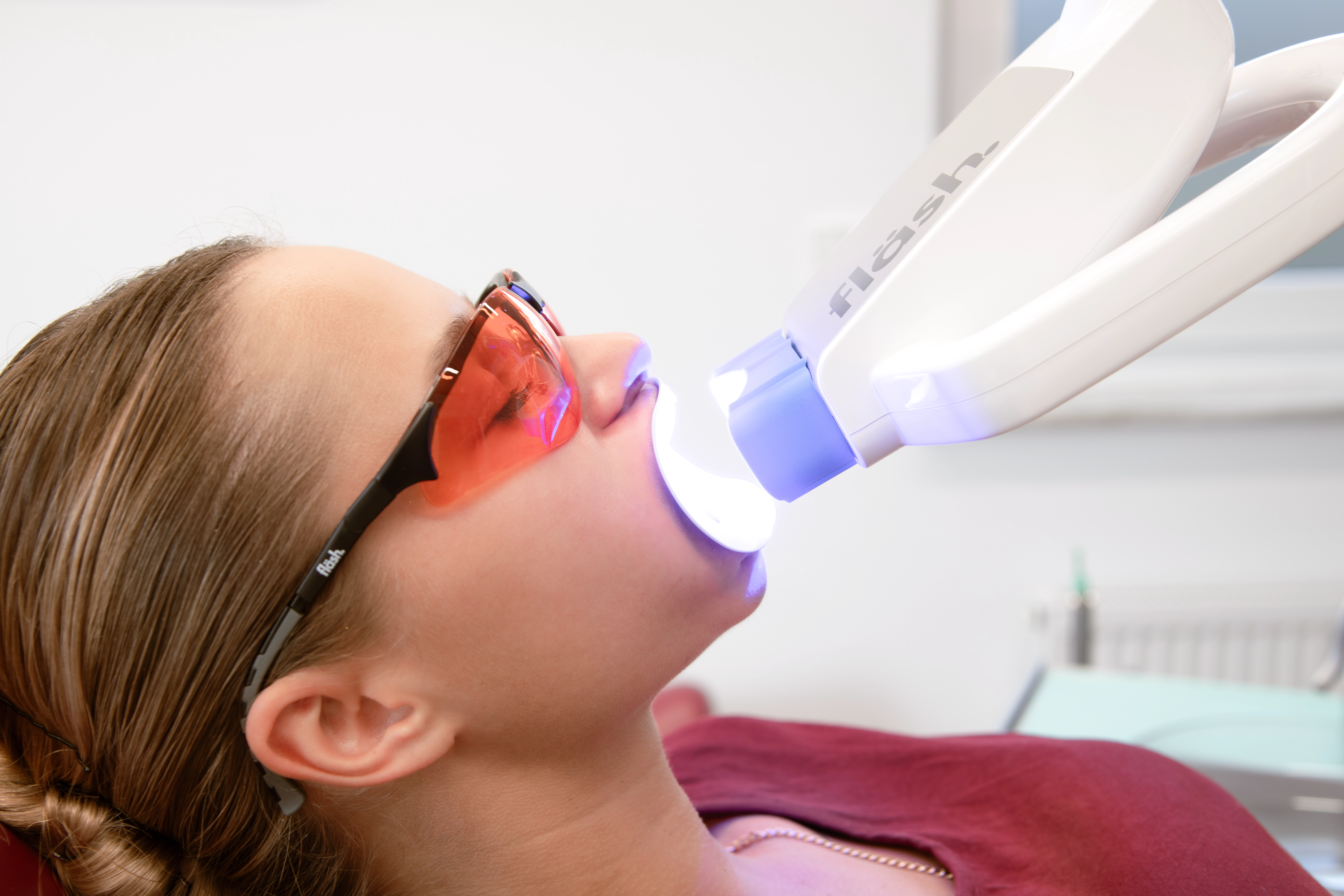 Patientin bei einer professionellen Zahnaufhellung mit LED-Licht in der kieferorthopädischen Praxis.